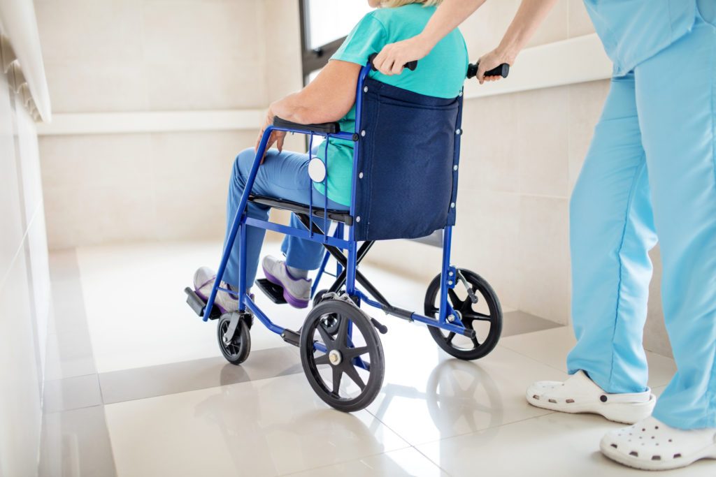 Low section of nurse pushing patient on wheelchair