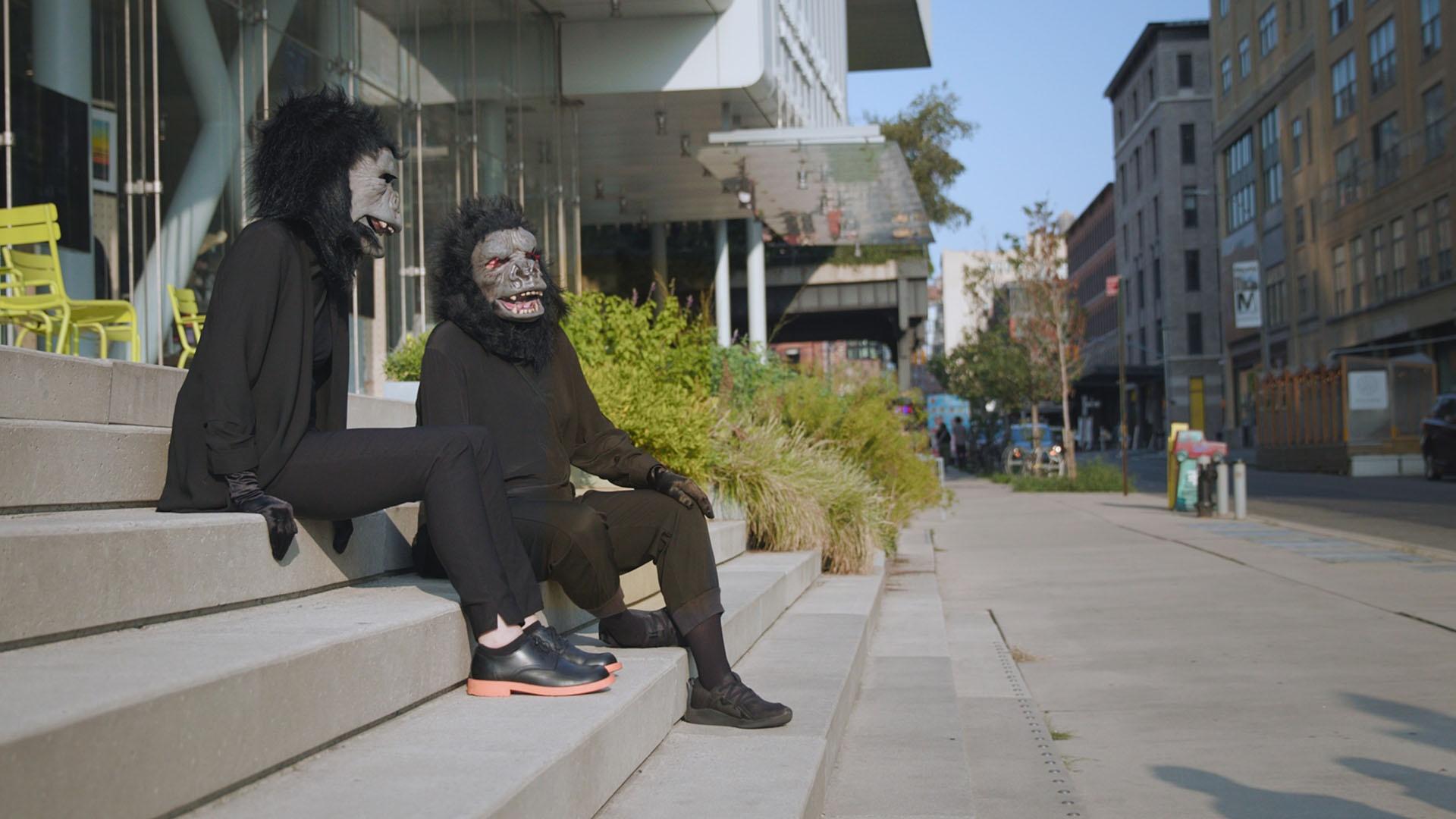 Two women in costumes sitting on the steps outside of the Whitney Museum of American Art.