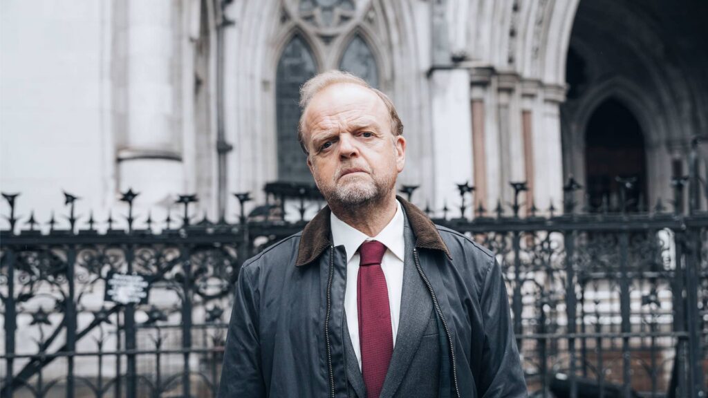 Toby Jones as Alan Bates standing defiantly in front of the Royal Courts of Justice in London