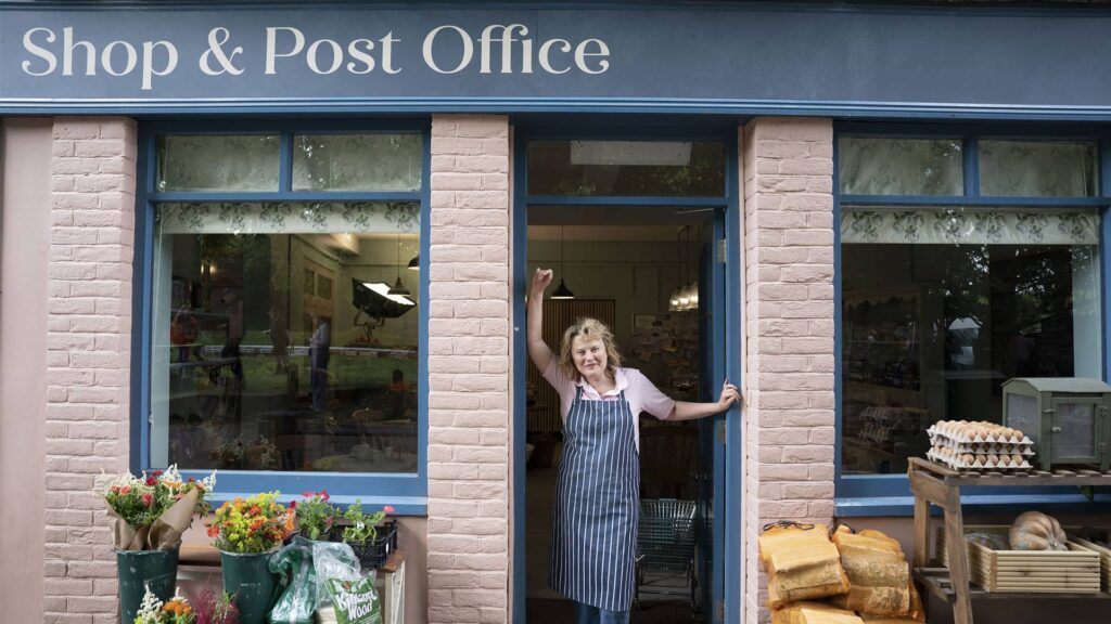 Monica Dolan as Jo Hamilton standing in the doorway of her post office